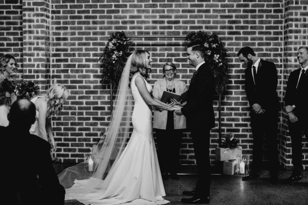 Couple taking their vows under copper arbour