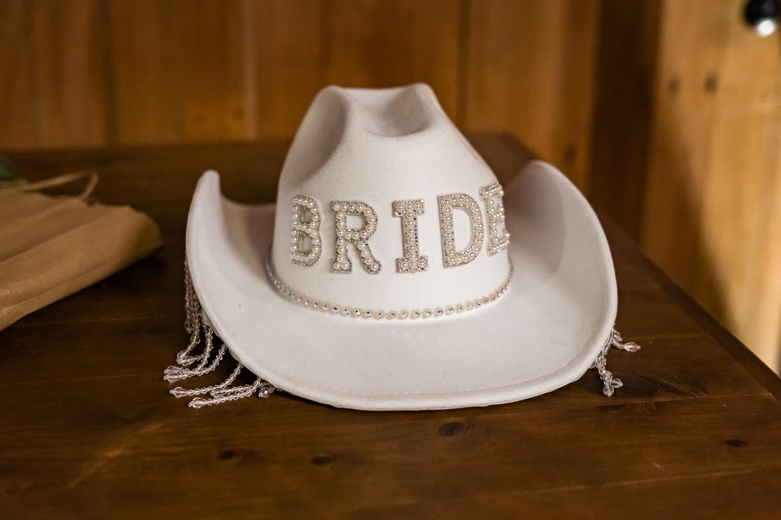 A photograph of a cream cowgirl hat with BRIDE lettered across the front