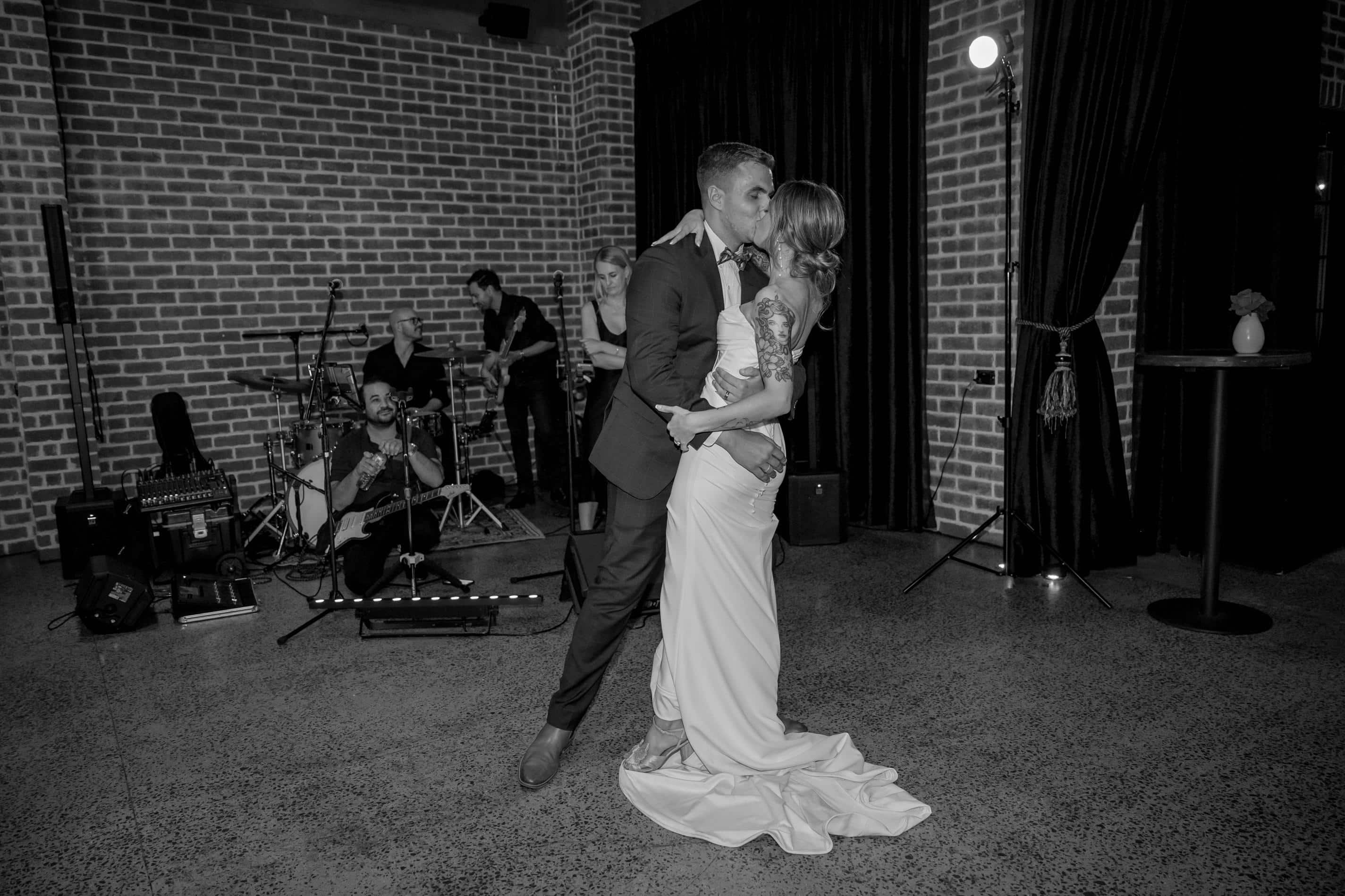 Indi and Jeremy kissing during their Factory51 wedding reception with Baker Boys Band performing
